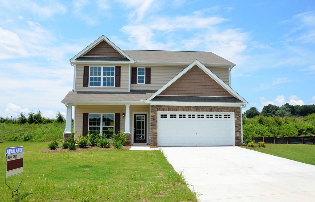 New two-story home with white gutters along the roof line and a green front lawn